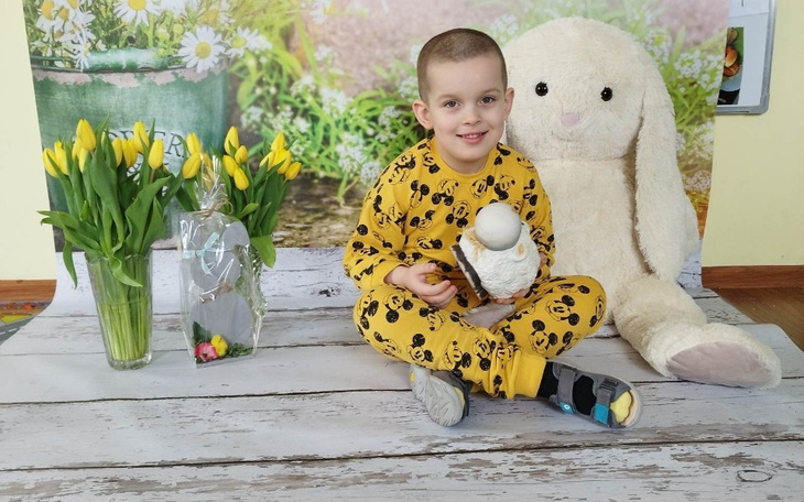 Chłopiec w żółtej piżamie trzyma figurkę, obok pluszowy królik.