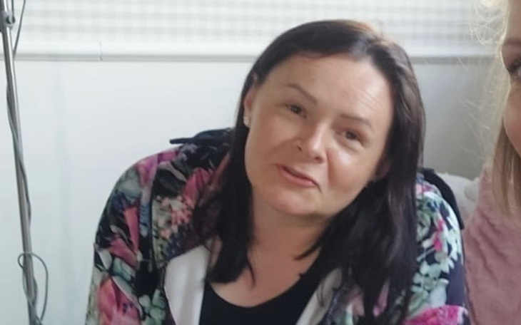 Kobieta w kolorowej bluzie, uśmiechająca się do kamery.