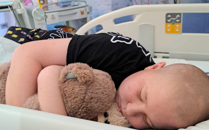 Chłopiec śpiący w szpitalu z pluszowym misiem.