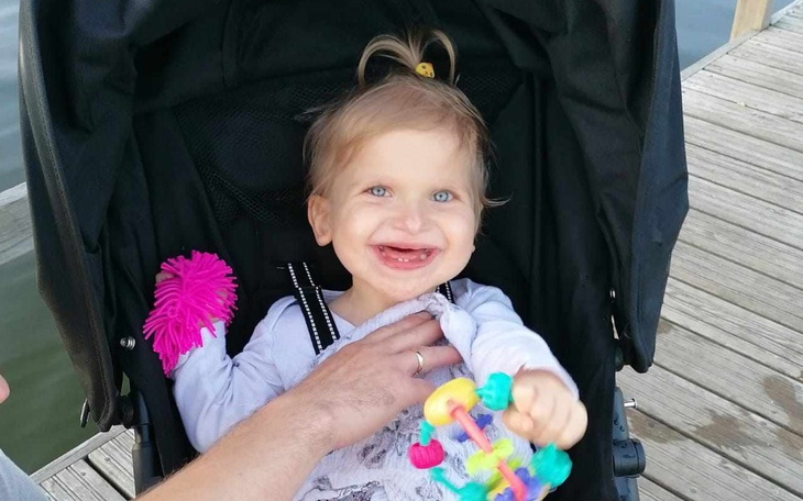 Małe dziecko w wózku, uśmiechające się do obiektywu.