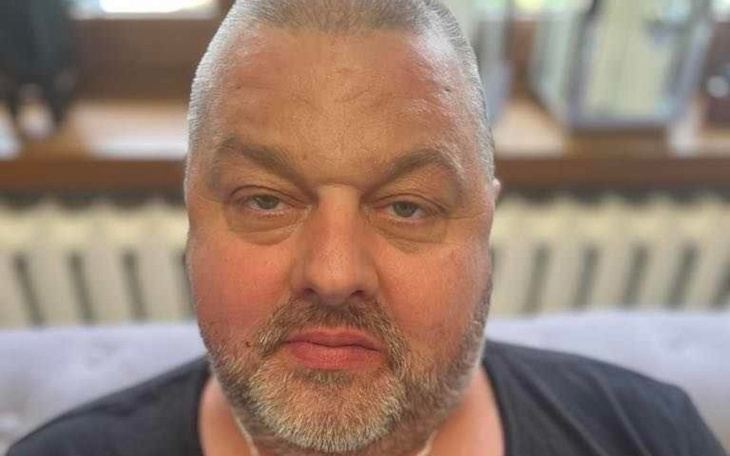 Mężczyzna z brodą siedzący na kanapie.