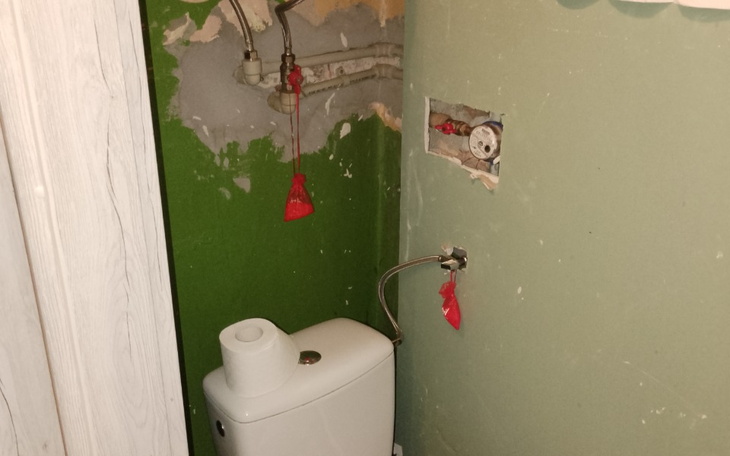 Widok na uszkodzoną ścianę w łazience z widocznym WC.