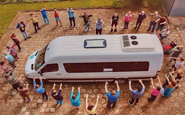 Grupa ludzi wokół busa, wspierających akcję.