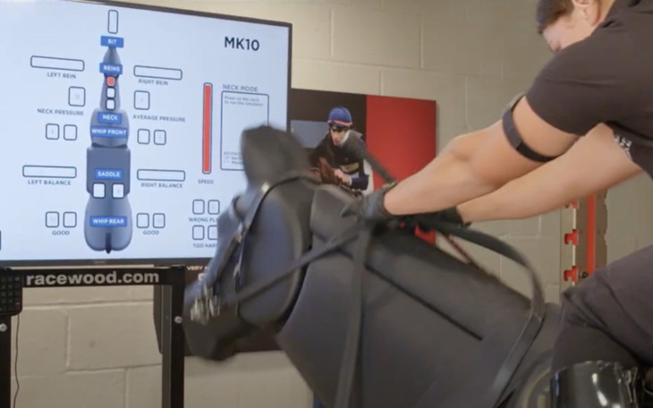Trening z symulatorem konia, monitor pokazujący parametry jazdy.