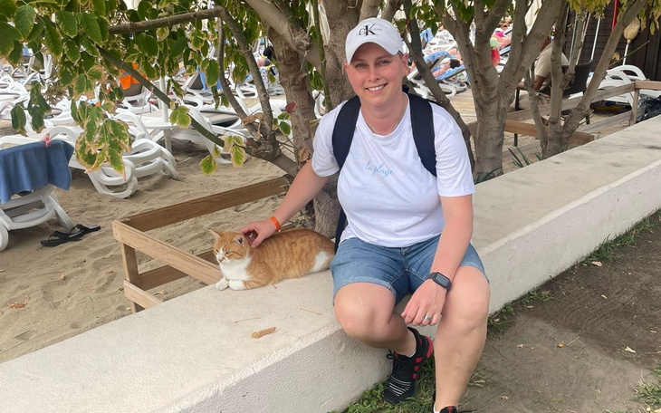 Kobieta siedząca na ławce z pomarańczowym kotem.