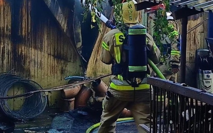 Strażak gaszący pożar w zniszczonym budynku.