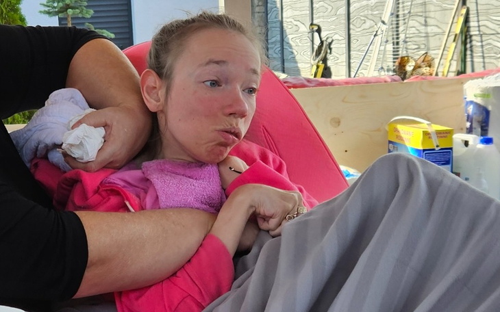 Kobieta w różowej bluzie, z wyrazem twarzy pełnym emocji.