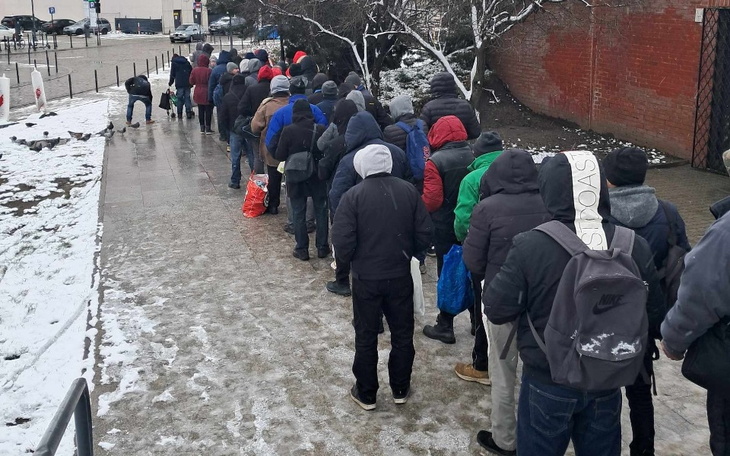 Ludzie stojący w kolejce na zewnątrz w zimowej scenerii.