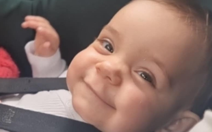 Uśmiechnięte dziecko w foteliku samochodowym, z radosnym wyrazem twarzy.