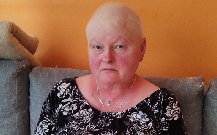 Kobieta z krótkimi włosami siedząca na kanapie, z poważnym wyrazem twarzy.