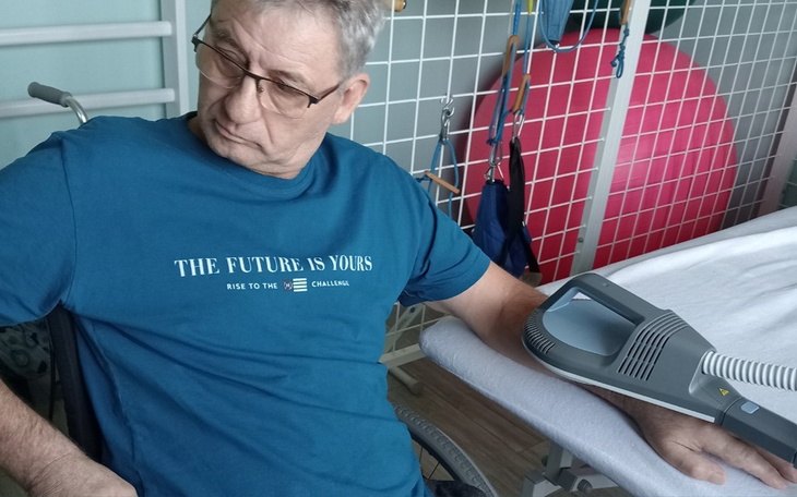 Mężczyzna w koszulce siedzi na wózku inwalidzkim.