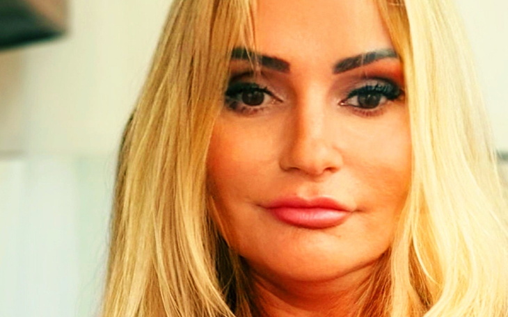 Portret kobiety z długimi blond włosami i wyrazistym makijażem.