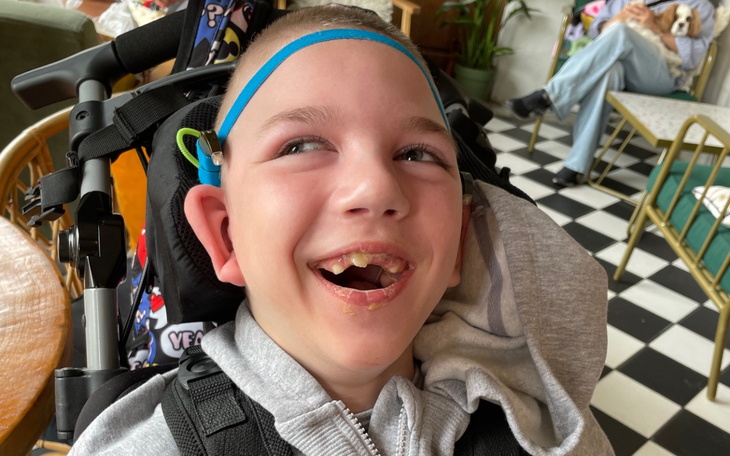 Uśmiechnięty chłopiec w wózku, z radością na twarzy.