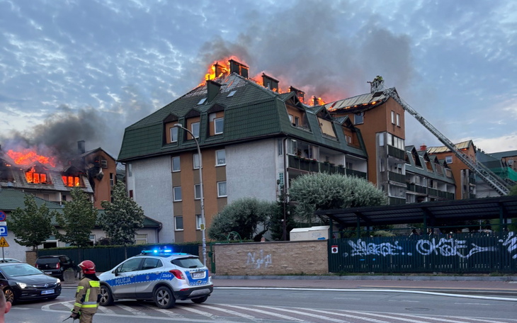 Pożar na dachu budynku, z widocznymi płomieniami i dymem.
