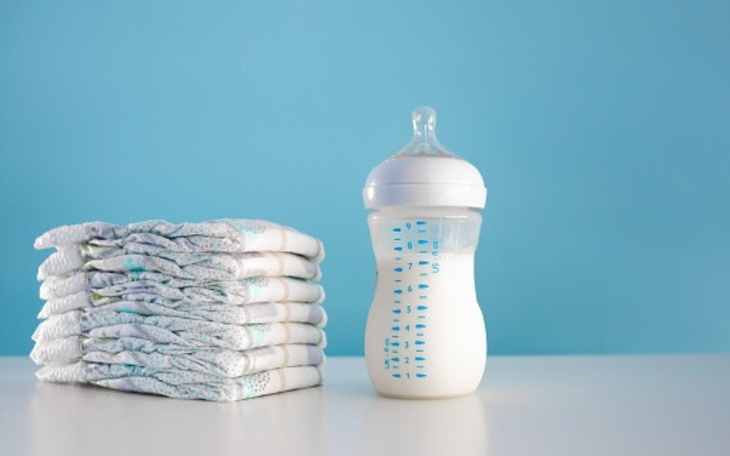 Butelka z mlekiem obok ułożonych pieluch.