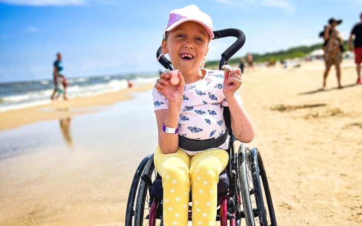 Dziecko i dorosły leżą razem na łóżku, uśmiechając się.