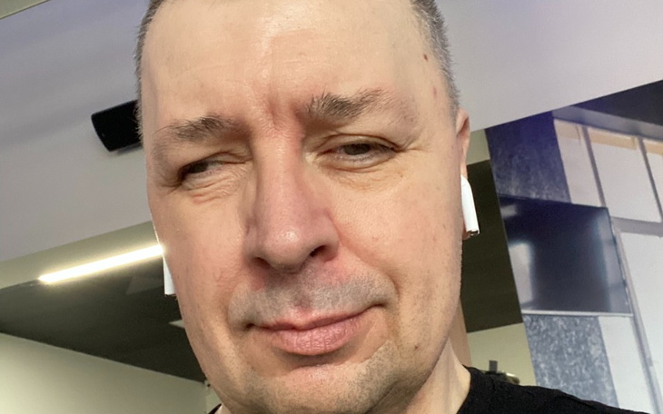 Mężczyzna w słuchawkach, uśmiechający się w siłowni.