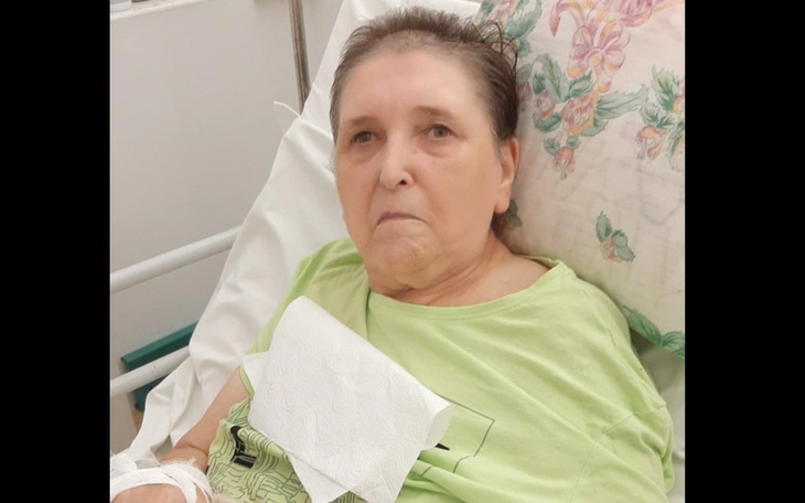 Kobieta w szpitalnym łóżku, z wyrazem powagi na twarzy.