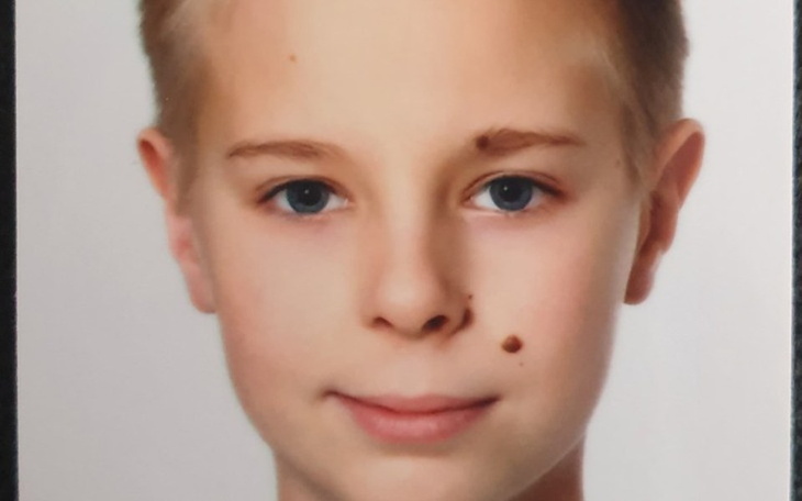 Portret chłopca z jasnymi oczami i uśmiechem.