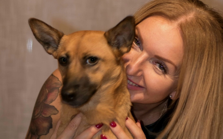 Kobieta z psem, obie uśmiechnięte do kamery.