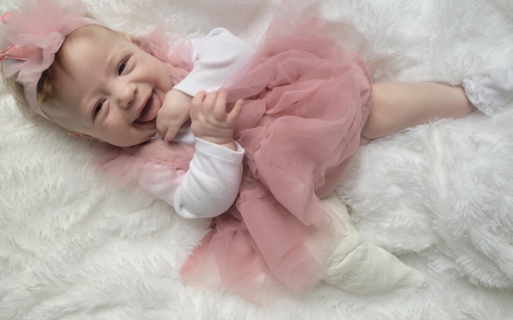 Mała dziewczynka w różowej sukience, uśmiechająca się.