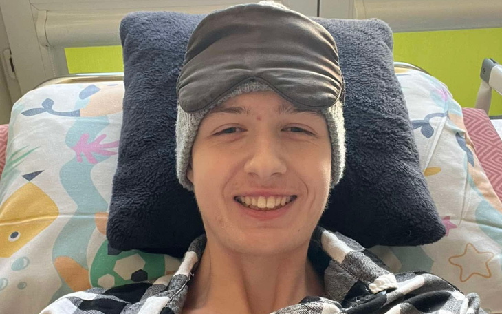 Młody mężczyzna w łóżku, uśmiechający się z opaską na oczach.