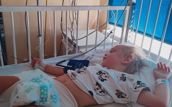 Małe dziecko leży w szpitalnym łóżku z monitorami.