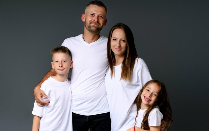 Rodzina pozująca do zdjęcia w białych koszulkach.