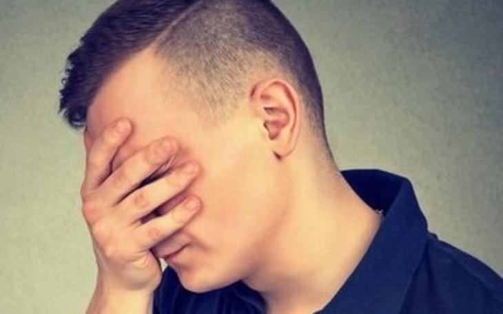 Mężczyzna z ręką na twarzy, wyrażający frustrację.