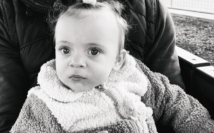 Mała dziewczynka z kokardą, patrząca z ciekawością w obiektyw.