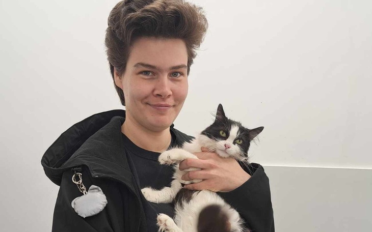 Osoba trzymająca kota w ramionach, uśmiechnięta i zadowolona.