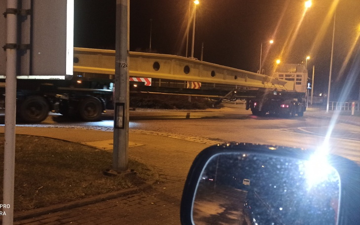 Transport dużej konstrukcji na rondzie w nocy.