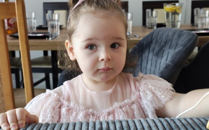 Mała dziewczynka w różowej bluzce, patrzy w obiektyw.