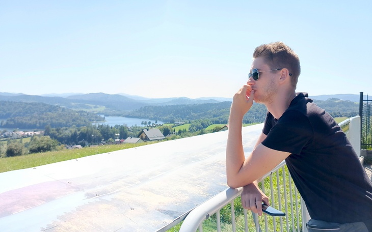 Mężczyzna w okularach przeciwsłonecznych podziwia widok na góry i jezioro.