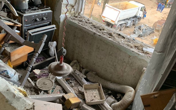 Zniszczona kuchnia z bałaganem i widokiem na plac budowy.