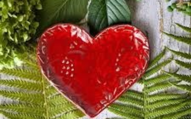 Czerwone serce na tle zielonych liści.