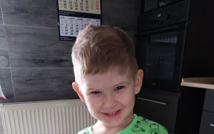 Chłopiec z krótkimi włosami, uśmiechający się w kuchni.