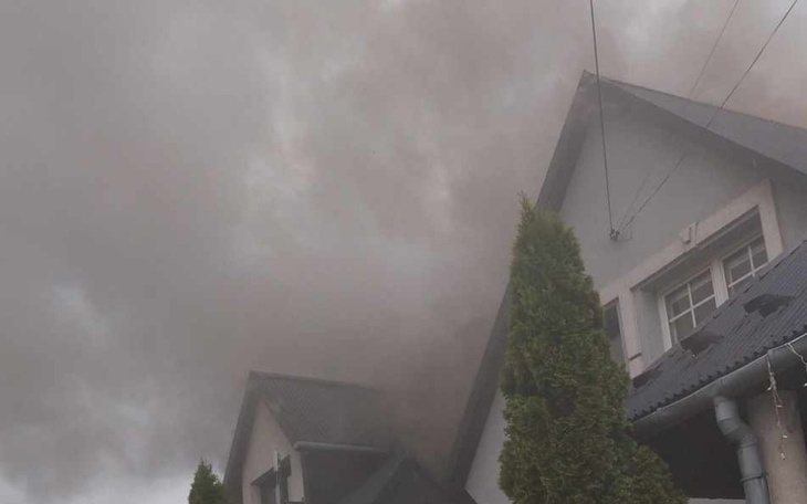 Dym wydobywający się z dachu budynku, w tle chmury.