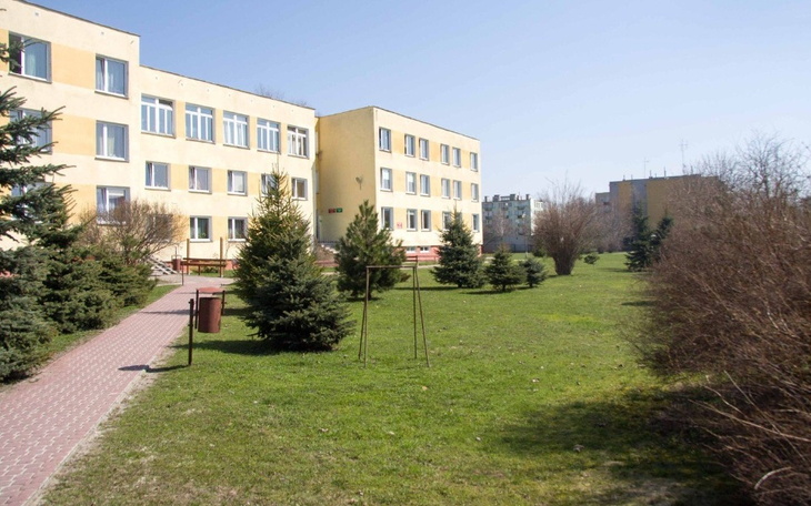 Widok na budynek z zielonym otoczeniem i alejkami.