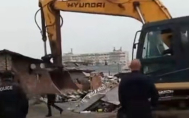 Maszyna budowlana burząca zniszczony budynek.