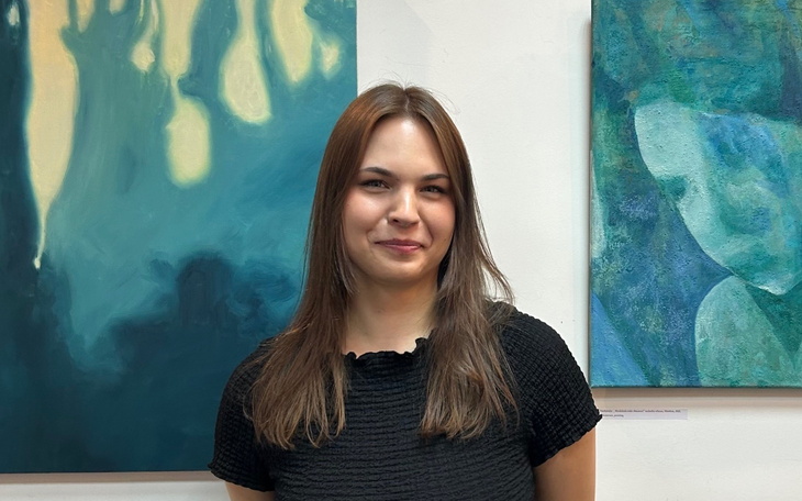 Portret młodej kobiety w galerii sztuki, z obrazami w tle.