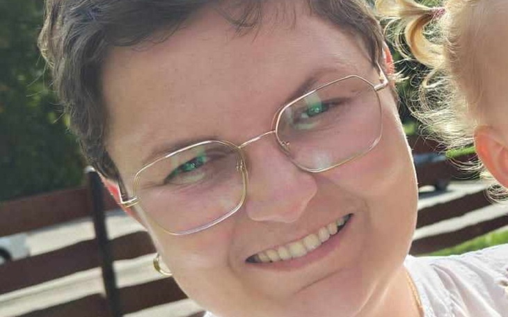 Uśmiechnięta kobieta w okularach, pozująca na zewnątrz.