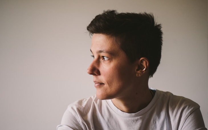 Kobieta z krótkimi włosami patrzy w bok.