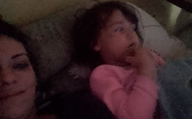 Mama i dziecko leżą w łóżku, oglądają coś na ekranie.