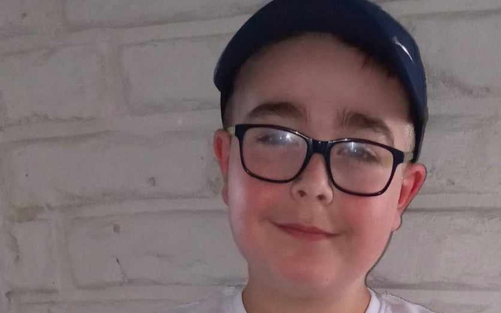 Chłopiec w okularach i czapce, uśmiechający się do kamery.