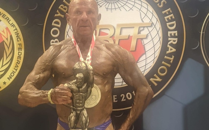 Mężczyzna z medalem na zawodach kulturystycznych, dumny z osiągnięcia.