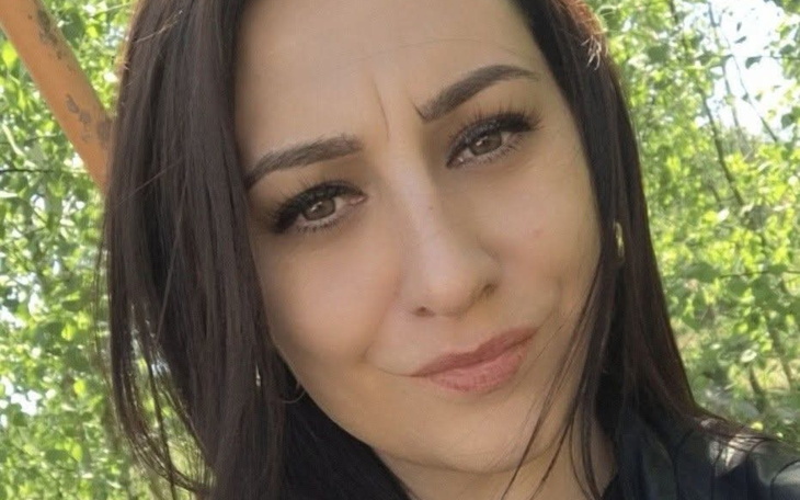 Portret kobiety w otoczeniu zieleni, uśmiechającej się do kamery.