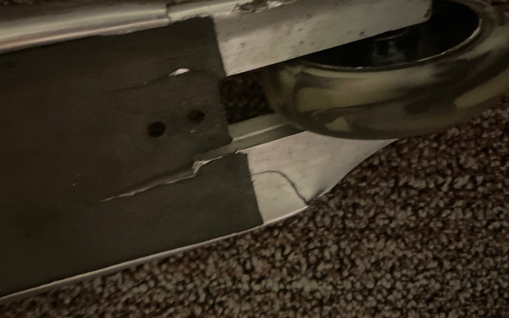 Uszkodzona hulajnoga na podłodze, widok na kółko i uszkodzenie.