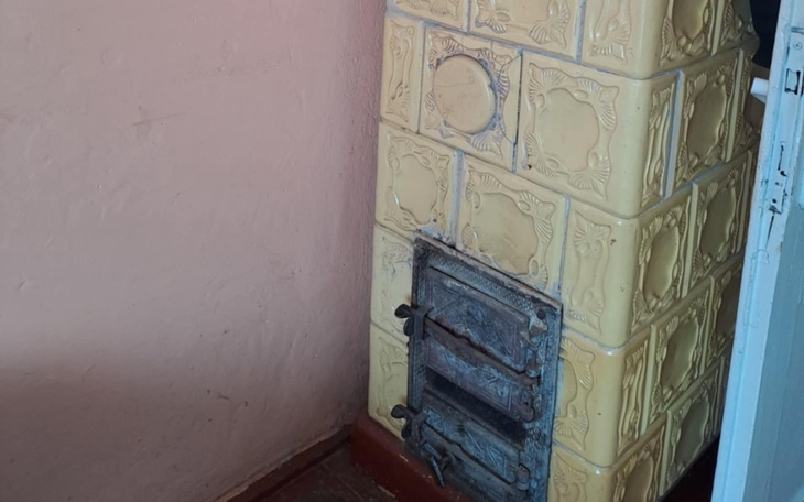 Stara piec kaflowy w kolorze żółtym, w kącie pokoju.