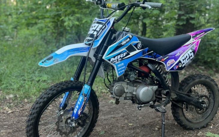 Motocykl terenowy na tle zielonej przyrody.